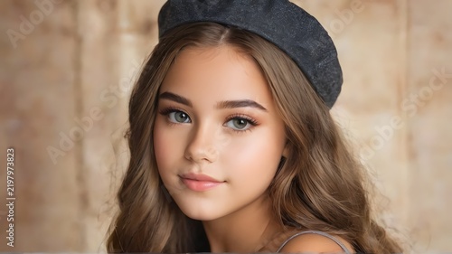 Portrait of a lovely young girl wearing beret hat looking at camera with neutral background