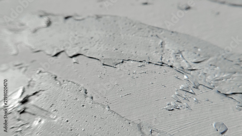A chaotic splash pattern of wet light grey stucco drying under natural light. spontaneous design, building renovation, abstract material, rough wall.