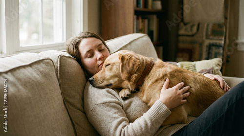 Adult woman relaxing on a sofa with a sleeping dog on her chest  