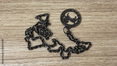 Bild auf Leinwand A tarnished silver chain with a round decorative pendant resting on a wooden surface