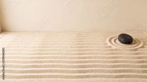 Raked sand garden with a single dark stone set in a swept circular hollow