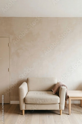 Single oat armchair against a muted clay lime washed wall in an empty room
