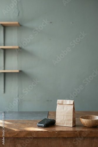 Card terminal and paper bag on a worn oak shop counter after closing