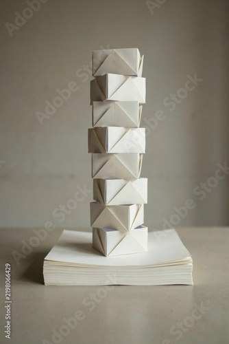 Tower of folded paper modules rising from a stack of blank cream sheets