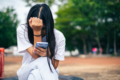 anxious worried teen girl with her smartphone as a conceptual backdrop for cyberbullying social media trauma, teenager mental health crisis, depression and panic attack