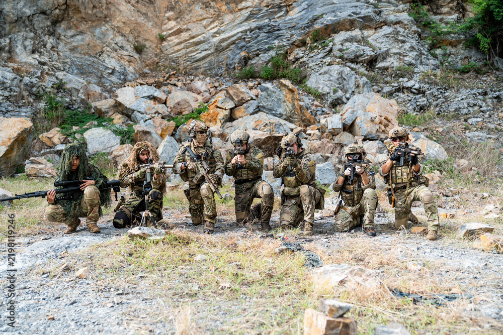 Obraz premium Military personnel train in rocky terrain during an exercise in an outdoor setting with various tactical equipment
