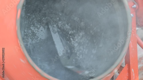 Concrete mixer blending mortar. Rotation of an orange concrete mixer drum with mixture inside, symbolizing production and the construction process
