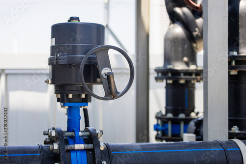 Industrial valve and pipeline system in a water treatment plant, butterfly valve with manual handwheel actuator on industrial pipe, large pipeline plumbing and control valve equipment in a factory