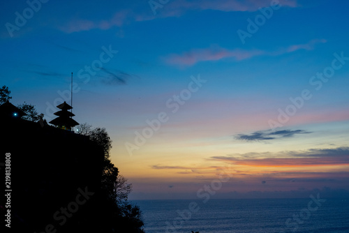 BALI, INDONESIA – OCTOBER 19, 2024: Silhouette of Uluwatu Temple pagoda on sea cliff during blue hour twilight in Bali island.