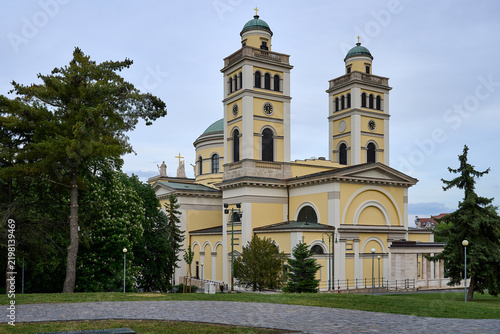 Neoclassical facade and towers of Eger Cathedral surrounded by trees and lawn in Eger, Hungary