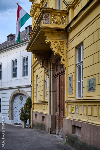 Historic yellow building decorated with a Hungarian flag along a quiet street in Eger, Hungary