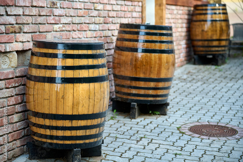 Oak wine barrels standing outside a traditional wine cellar on a paved alley in Eger, Hungary