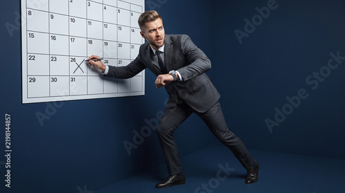 Businessman Writing on Wall Calendar for Schedule Planning