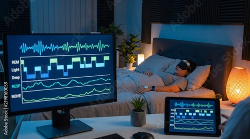 Person sleeping in bed while being monitored by a sleep tracking system at night.