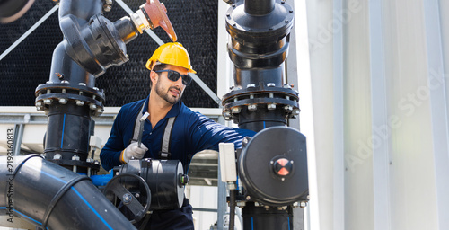 Engineer in hard hat inspecting industrial valves and pipelines, technician checking mechanical pipe system and equipment in a factory, worker monitoring water treatment plant and control valves