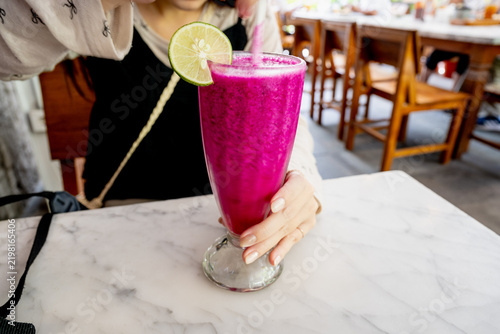 Fresh red dragon fruit smoothie and iced lime mint drink on marble table in a cafe.