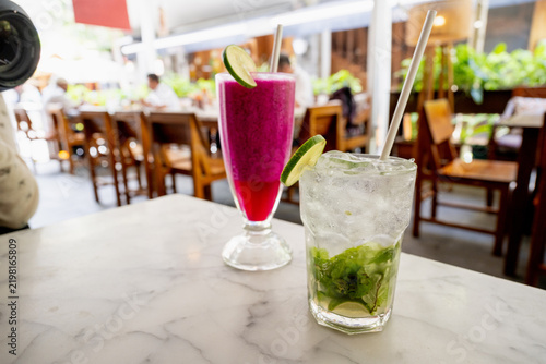 Fresh red dragon fruit smoothie and iced lime mint drink on marble table in a cafe.