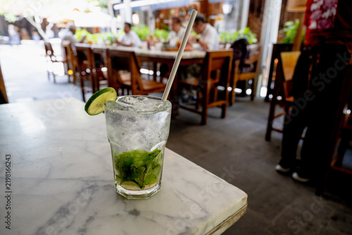 Refreshing iced lime mint soda drink on a marble table in an outdoor cafe.