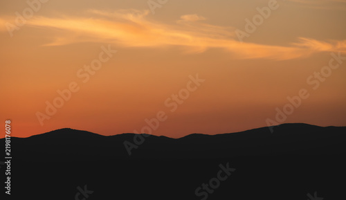 Atardecer en la Sierra de Guadarrama, en Madrid, España. Cielo anaranjado con los últimos rayos de sol resaltando la silueta de las montañas situadas al norte de Madrid.