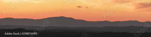 Atardecer en la Sierra de Guadarrama, en Madrid, España. Cielo anaranjado con los últimos rayos de sol resaltando la silueta de las montañas situadas al norte de Madrid.