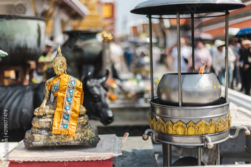 фотографія Gilded Buddha Statue and Incense Burner in Thai Temple Courtyard