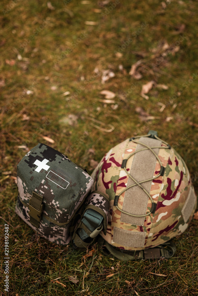 Obraz premium Tactical military helmet and medical IFAK pouch on ground