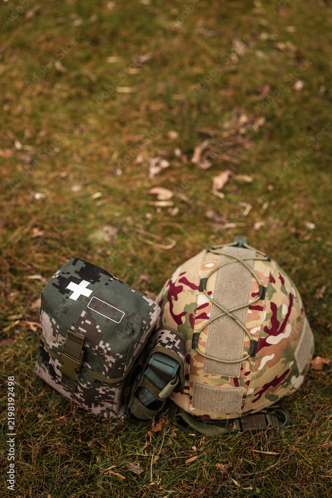 Fototapeta premium Tactical military helmet and medical IFAK pouch on ground