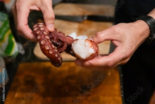 Hands holding sliced boiled octopus tentacle close up