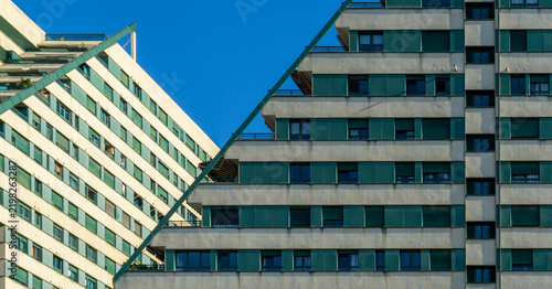 Edificios Politaria showcasing modern ziggurat architecture with cascading terraces and repeating green window shutters against a clear blue sky, forming abstract geometric patterns