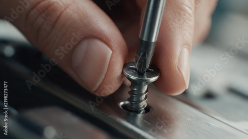 Macro Close-up of Hand Tightening Screw with Screwdriver