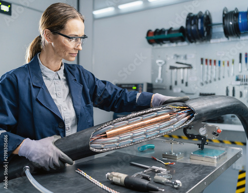 Female Technician Inspecting Cutaway Section of High Voltage Submarine Cable