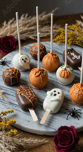 Halloween-themed cake pops and candies on a decorative platter  