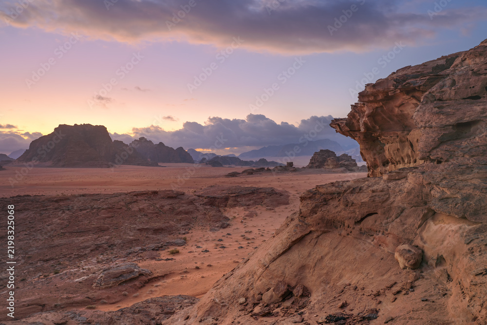 Obraz premium Morning at Wadi Rum desert, orange pink sky above calm red dust arid landscape with rocky formations, scene reminiscent of planet Mars