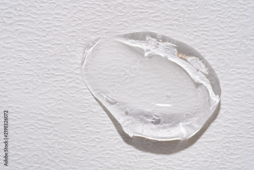 Clear cosmetic gel drop swatch on white paper. Transparent hyaluronic acid smudge, moisturizing face liquid lotion or aloe vera serum sample