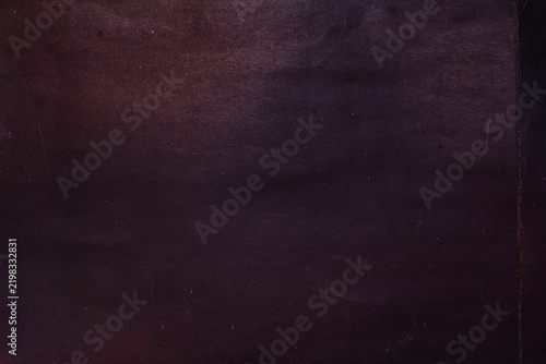 A rough, creased paper surface, with a background of crumpled black paper.
