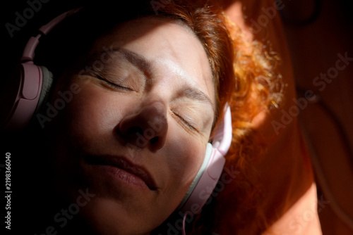 Woman relaxing listening music with headphones in sunlight