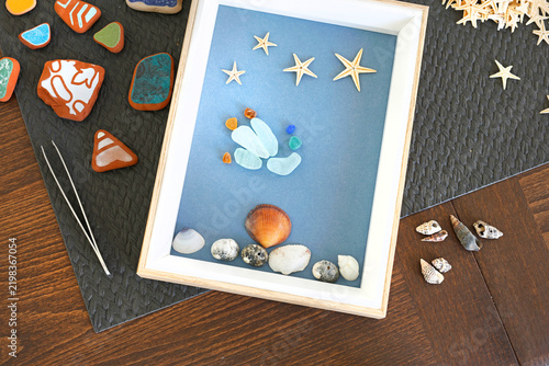 Upcycled sea glass shadow box beach decor craft. Eco friendly sustainable home decor styling. Creative summer hobby DIY workshop backdrop.