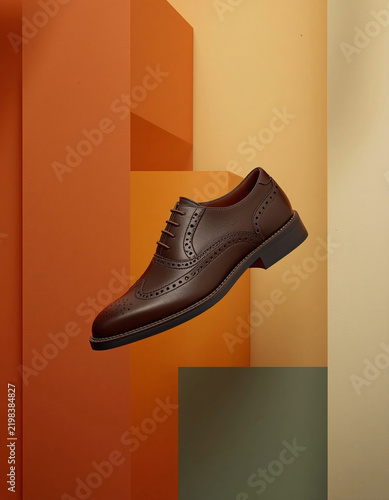 Stylish men's brown leather brogue sneaker suspended against a warm geometric layered background 