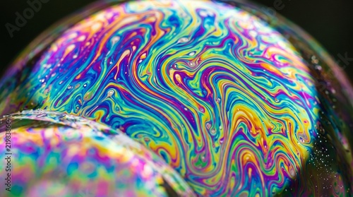 Iridescent soap bubble surface showing swirling rainbow patterns and vibrant liquid reflections captured in high resolution macro photography style closeup shot