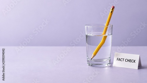 Bent pencil in glass of water with fact check sign