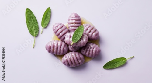 Fresh purple potato gnocchi pasta served with green sage leaves on top