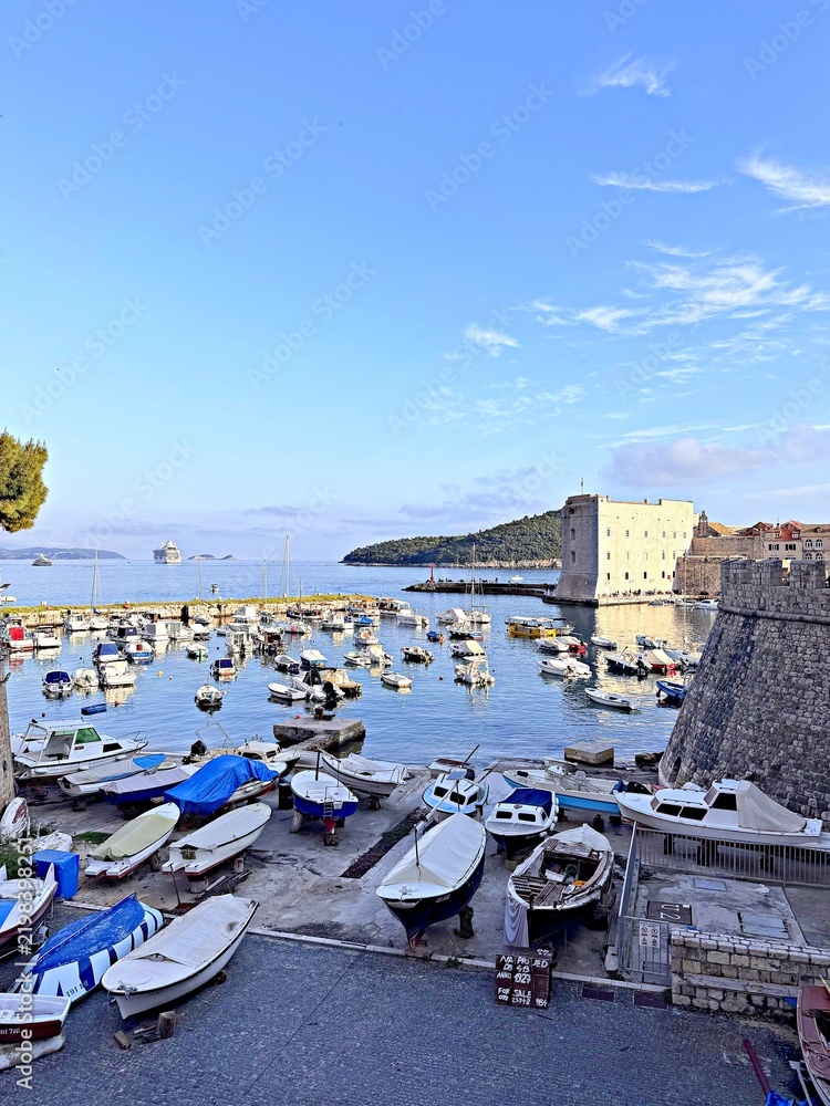 Fototapeta premium Boats docked in a harbor with a fort in the background