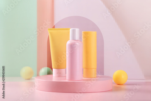 A vibrant and playful still life of unbranded cosmetic packaging featuring a pink bottle and two yellow tubes. sun care branding, summer skincare lines, or boutique beauty product marketing.