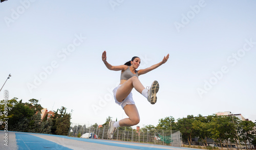 Young woman performing long jump on outdoor track