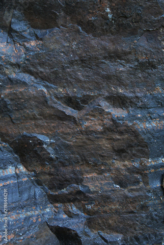 Rugged dark stone surface with bluish grey tones and brown mineral streaks