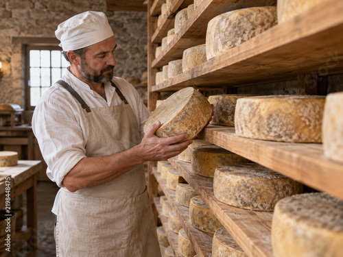 Cheesemaker inspecting aged cheese wheels in artisan cellar