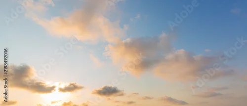 Panel kuchenny z motywem Panoramic Golden Hour Sky with Soft Clouds at Sunset,A wide panoramic photograph of a soft sunset sky featuring golden-lit clouds against a blue and pale yellow gradient backdrop. Ideal for web header