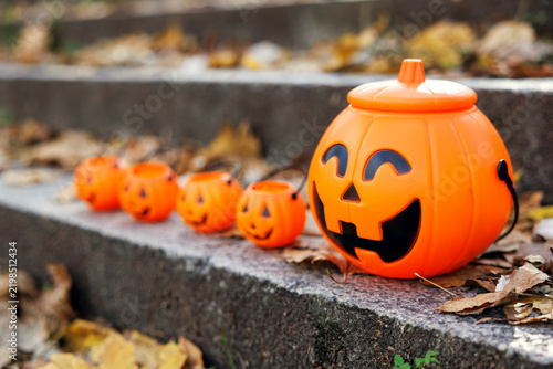 Plastic pumpkin buckets arranged on outdoor steps with autumn leaves