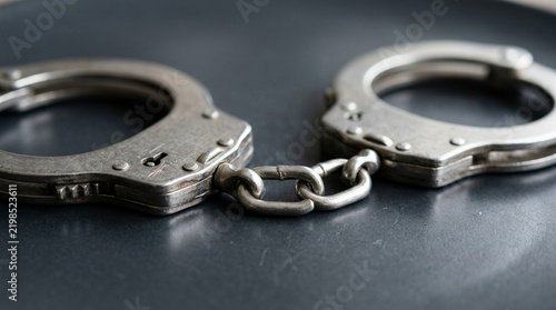 Close-up of Metal Handcuffs on Dark Surface, Symbol of Justice and Law Enforcement