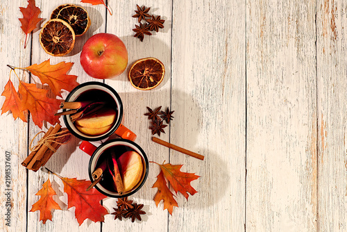 Quadro su tela Two enamel mugs with hot mulled wine, cinnamon sticks, nuts, dried orange slices, star anise, and fallen maple leaves